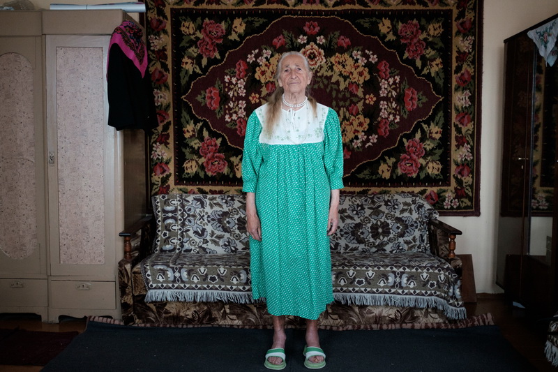 Вера ў сукенцы, якую ёй падаравала нявестка. Вера была ўжо на пенсіі, калі яе сын ажаніўся. Бацькі нявесткі былі супраць гэтага шлюбу. Вера пасяліла маладых у сябе і дапамагала ім гадаваць першынца. 