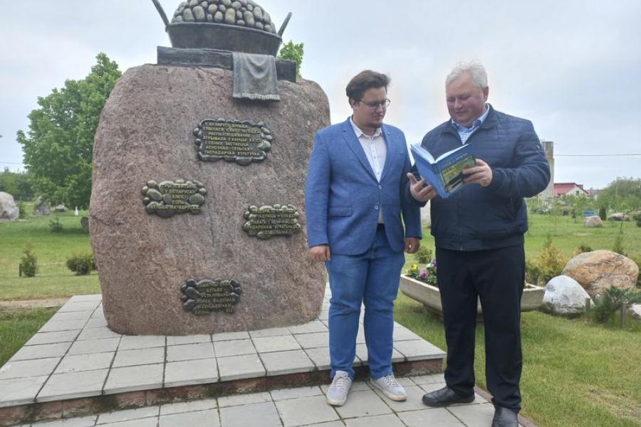 Юрый і Ілья Лойкі з кнігай Вадзіма Вікенцьевіча «След на зямлі»  побач з адным з такіх «слядоў» — памятным знакам бульбе.
